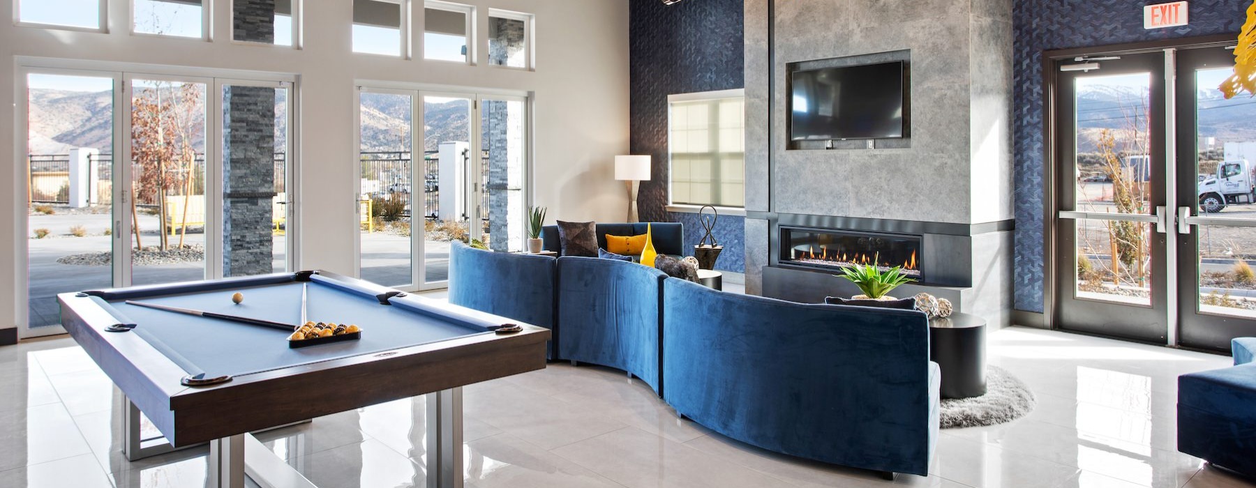 a lounge with a pool table, couch and a tv